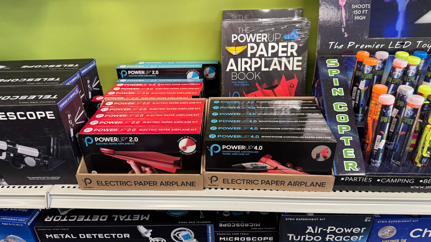 Assorted toys including electric paper airplanes and LED toys on a shelf.