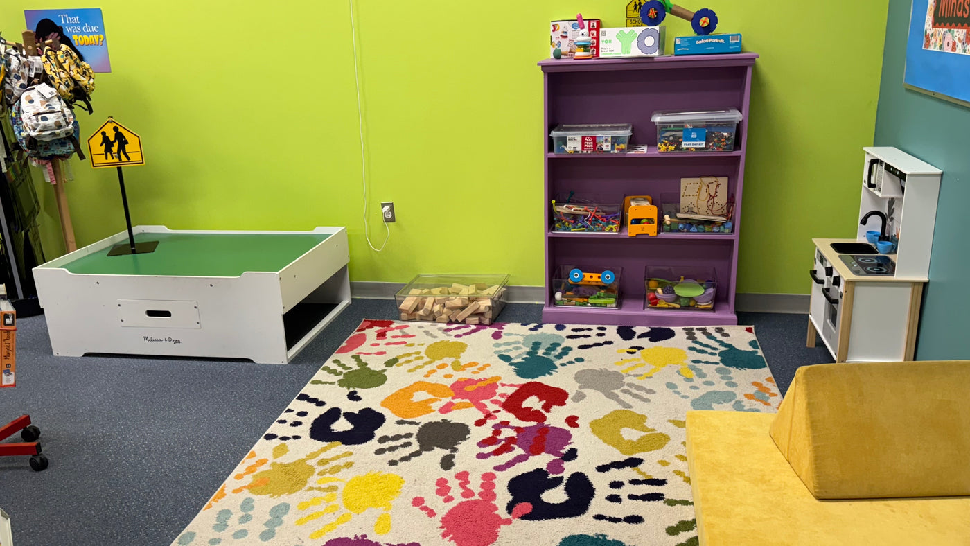 Children's play area with colorful rug, bookshelf, and toys.